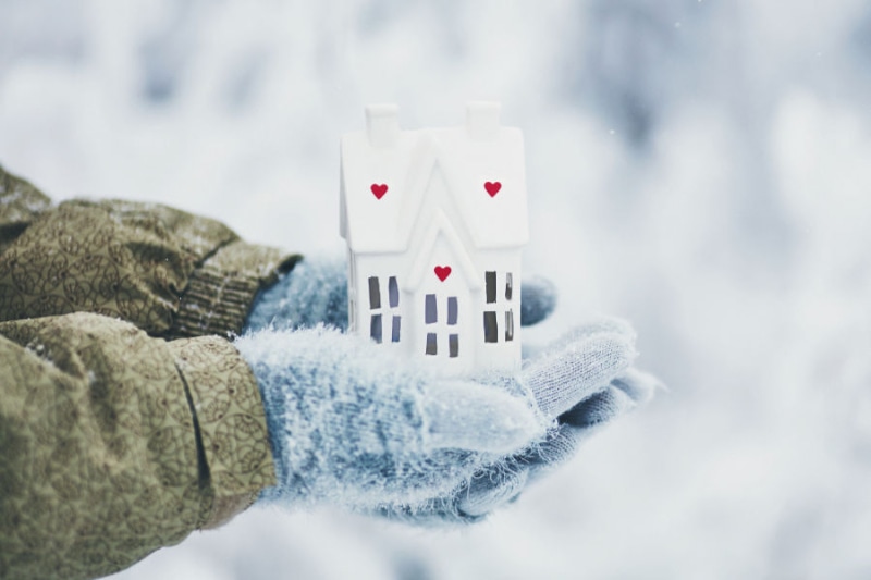 Protect Your Plumbing From Freezing Weather. Gloved hands holding house in winter.