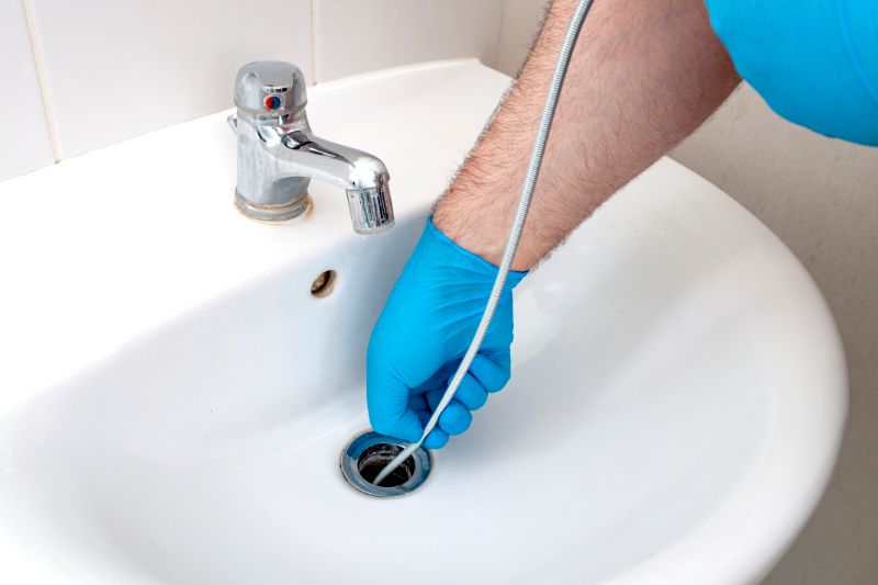 Image of person cleaning a clogged drain. Why Do My Drains Keep Clogging?